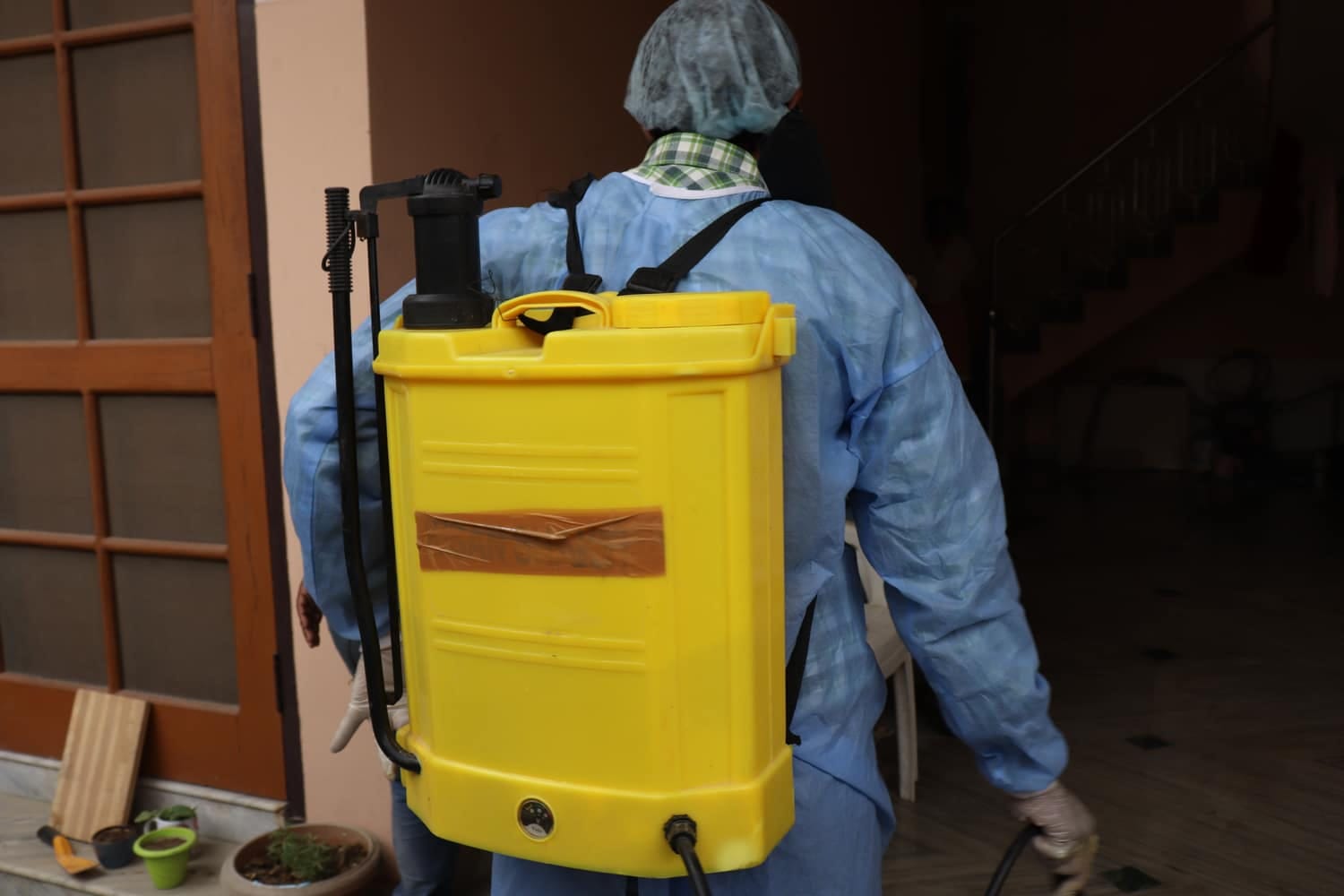 Professionnel en tenue de protection réalisant une désinfection de locaux